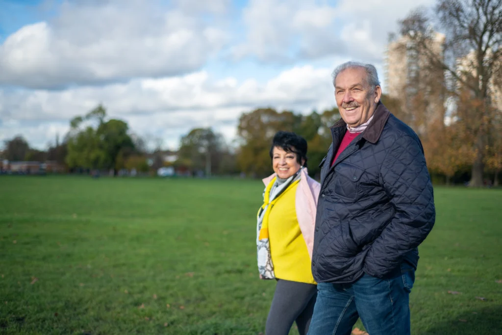 A middle aged man and woman walking through a park